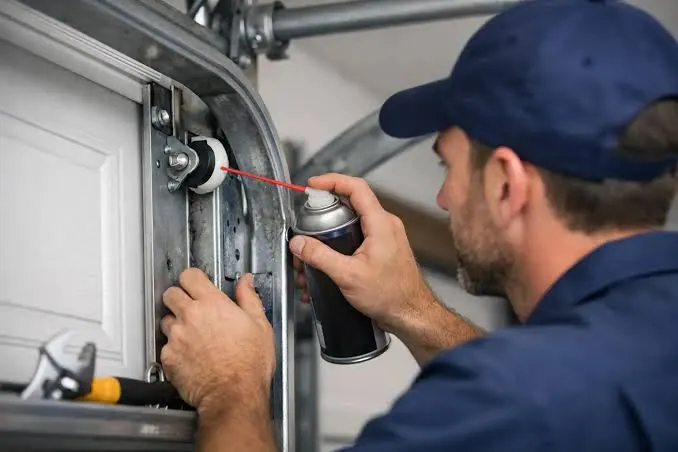 Residential garage door technician inspecting opener, tracks and door hardware